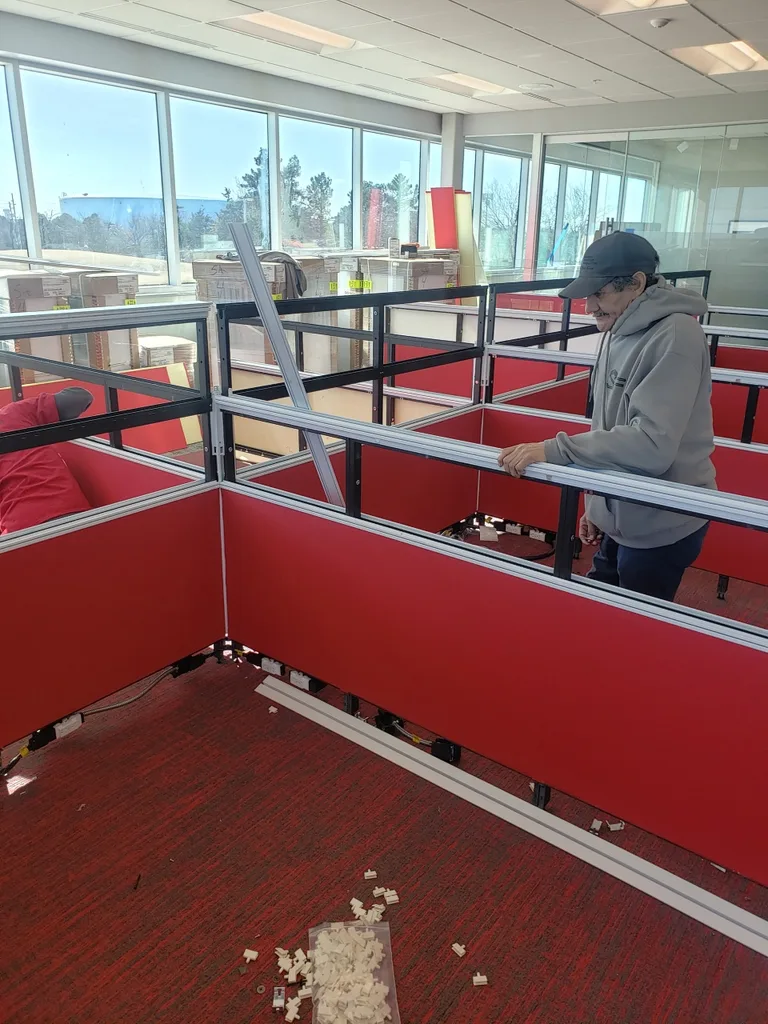 A mover assembling red office workstations during an office moving project